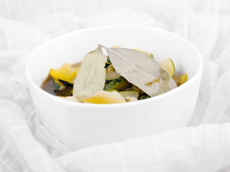 Delicious vegetarian soup made from zucchini and yellow paprika served in white porcelain bowl