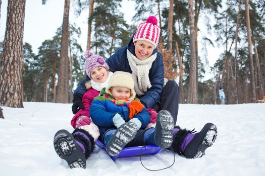 Two kids with mother is sledging in winter-landscape