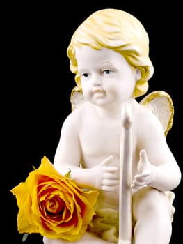 Ceramic cupid figure with tea rose on black background