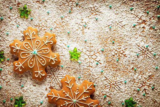 Gingerbreads on snowflakes background made of icing sugar on wooden table. Christmas composition. Top view