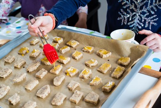 Girl decorating cookies for Christmas on a baking tray