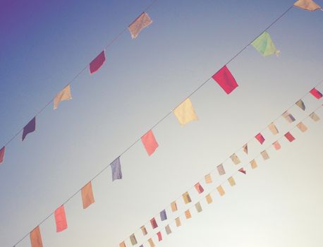 Colorful bunting flags on blue sky with retro filter effect