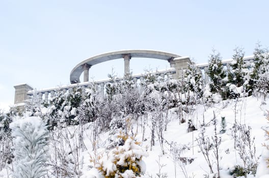 cement columns observation deck on a high snowy mountain planted thuja in cold winter time