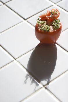 Viviparous (seeds sprouting inside) a red tomato sitting on a white tile countertop.