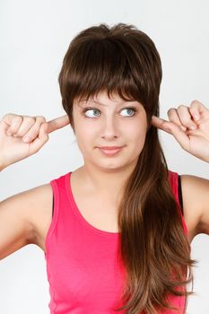 Young attractive girl covers her ears finger