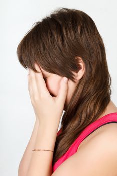 Young attractive girl closes her eyes with her hands