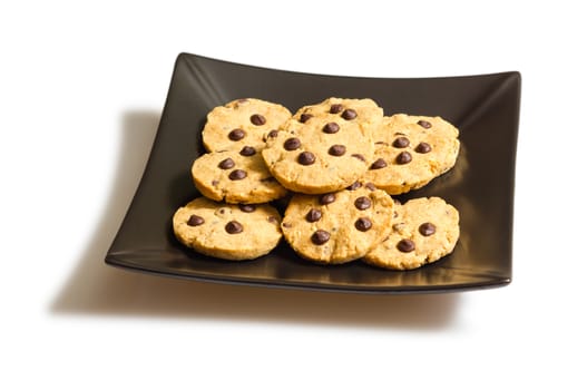 Pile of chocolate chip cookies in a square black plate, isolated on white background