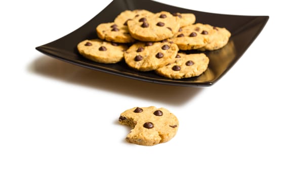 Pile of chocolate chip cookies in a square black plate, isolated on white background