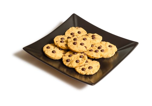 Pile of chocolate chip cookies in a square black plate, isolated on white background