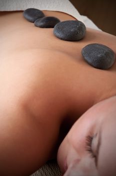 Young woman lying in a spa ready to get a massage with rocks on her back