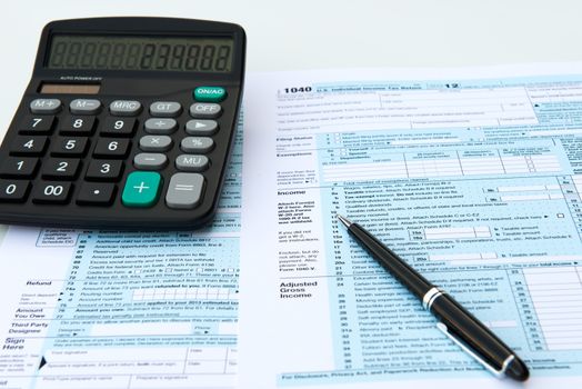 Filling out income tax forms with calculator and pen