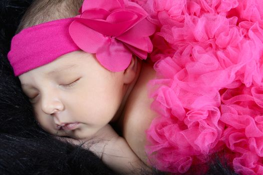 Sleeping baby girl wrapped in pink tutu with headband