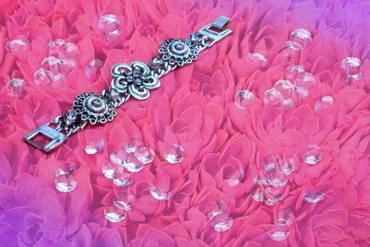 Silver bracelet on pink floral background with gems