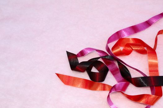 Colorful satin ribbons on a pink background