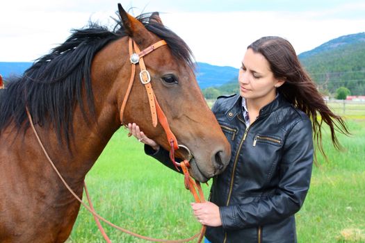Brunette caucasian female with horse in a field