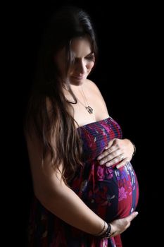 Pregnant brunette female on a black background