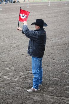 MERRITT; B.C. CANADA - MAY 15: Unidentified cowboy and marshall holding up a red flag at Nicola Valley Rodeo on May 15; 2011 in Merritt; British Columbia; Canada
