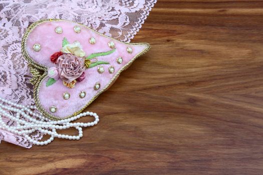 Fabric heart and pearls on wooden table