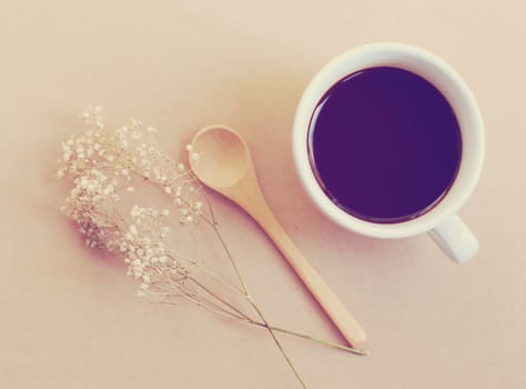 Black coffee and spoon with dried flower, retro filter effect