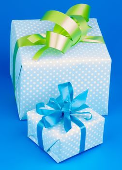 Two Gift Boxes with Green and Blue Bow isolated on Blue background