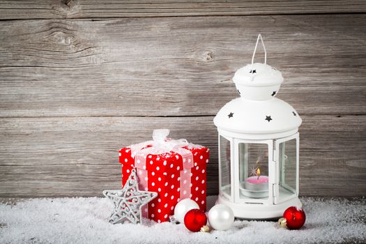Burning lantern in the snow with christmas decoration, on wood background,
