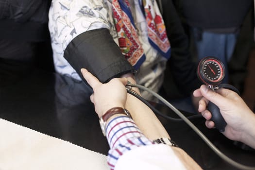 Doctor/nurse checking senior woman blood pressure