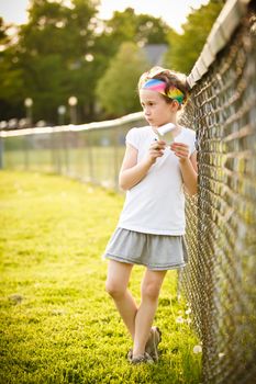 Little girl writing outside on the grass at the golden hour