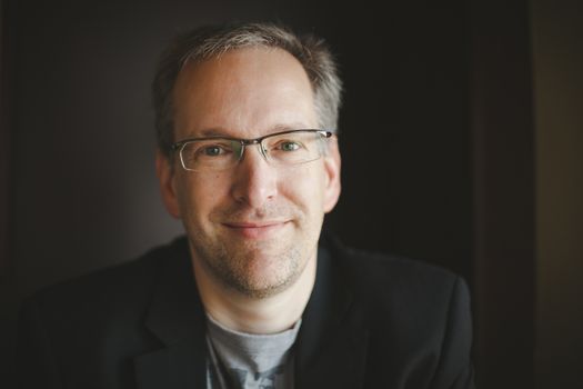 Man wearing a jacket sitting in a restaurant and smiling