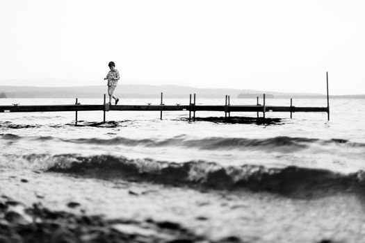 Boy walking on a wharf on a lake