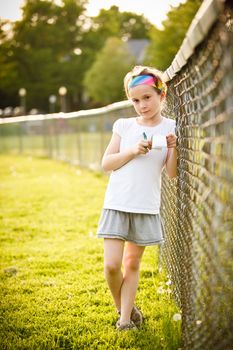 Little girl writing outside on the grass at the golden hour