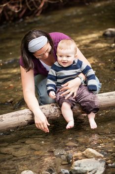 Mother and son playing on a tree trunk in a river