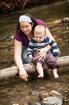 Mother and son playing on a tree trunk in a river
