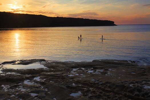 Silhouette of some stand up paddle boarders enjoying the calm seas and a beautiful sunrise on Botany Bay, Australia  SUP is a fairly new sport based on the Hawaiin Hoe he'e nalu. 