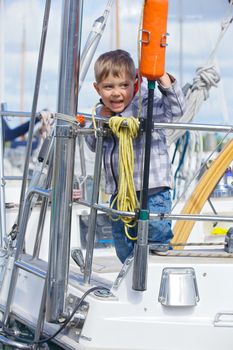 Cute happy boy rests on Yacht Club and is glad at life.