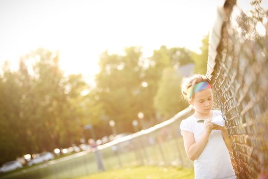 Little girl writing outside on the grass at the golden hour