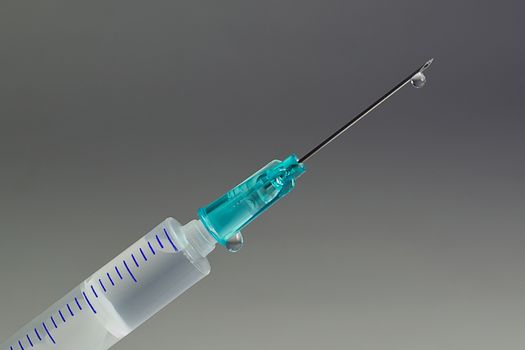 A macro shot of a hypodermic needle with a droplet of fluid. Illustrates many concepts, from health care to drug abuse.