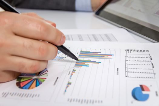 Businessman reviewing chart documents with digital tablet computer in the workplace