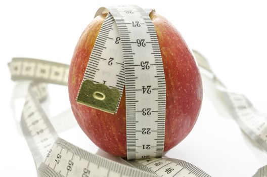 Measuring tape wrapped around apple. Isolated over white background. Weight loss concept.