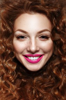 Emotional portrait of a girl with curly red hair (ginger) and freckles. Lip color "fuchsia".