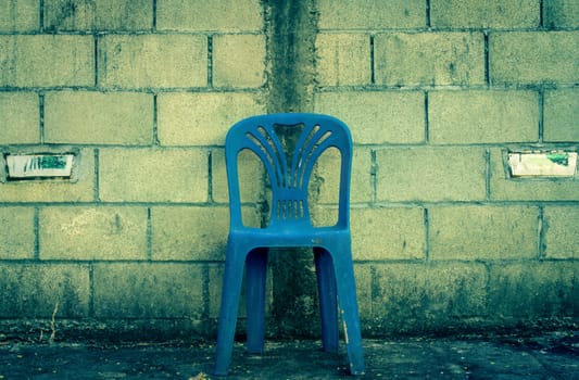 One center blue chair on concrete block background in vintage style with soft light