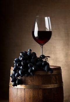 Wine goblet with wooden barrel and grape