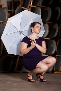 Female Actress in a purple dress with a white umbrella is squatting on stage