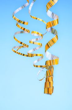 Three Yellow Striped Hanging Down Curled Party Streamers isolated on Blue background