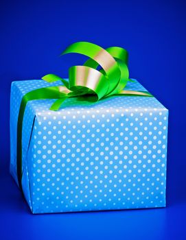 Gift Box with White Polka Dot, Green Ribbon and Bow isolated on Blue background