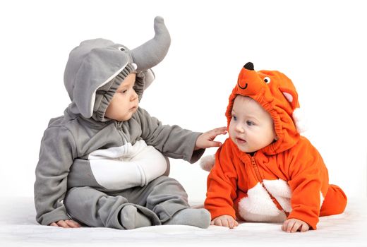Two baby boys dressed in animal costumes playing over white background