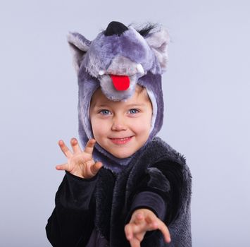 A portrait of a little boy trying a carnival suit of wolf on the grey background