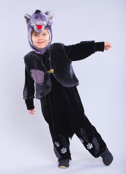 Little boy trying a carnival suit of wolf on the grey background
