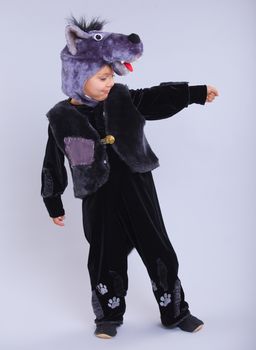 Little boy trying a carnival suit of wolf on the grey background