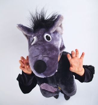 A portrait of a little boy trying a carnival suit of wolf on the grey background