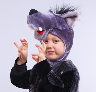 A portrait of a little boy trying a carnival suit of wolf on the grey background